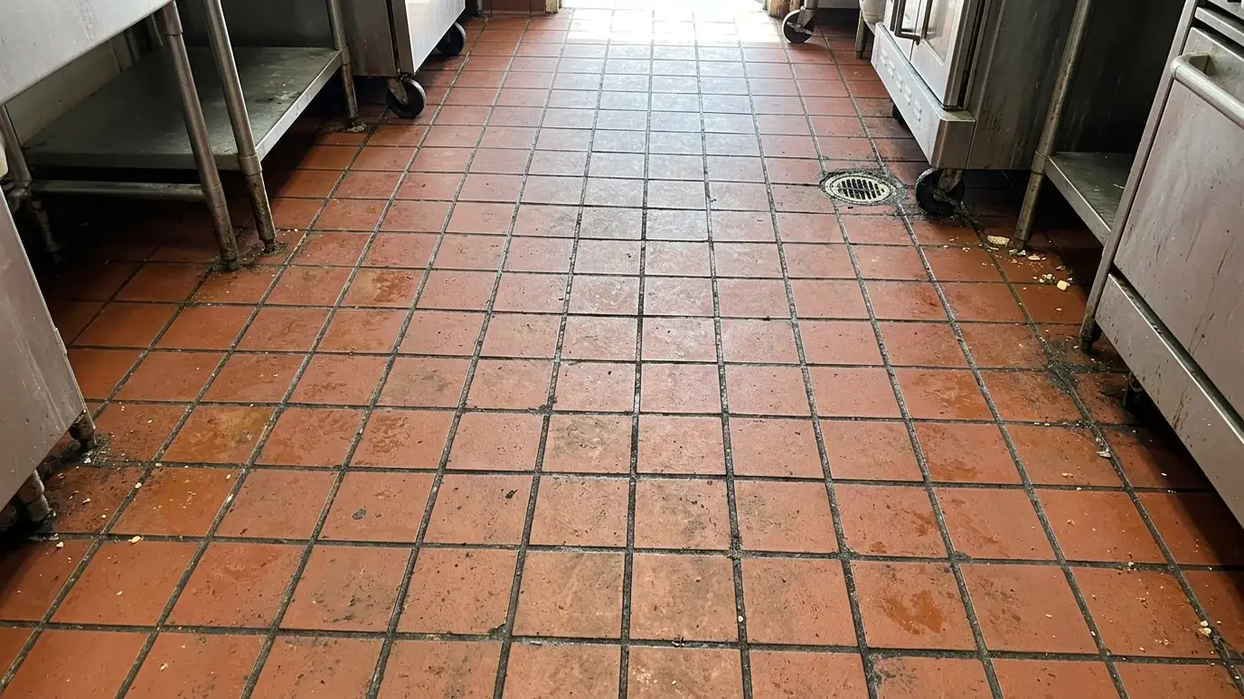 Before: a commercial kitchen floor with red quarry tile with greasy, blackened grout